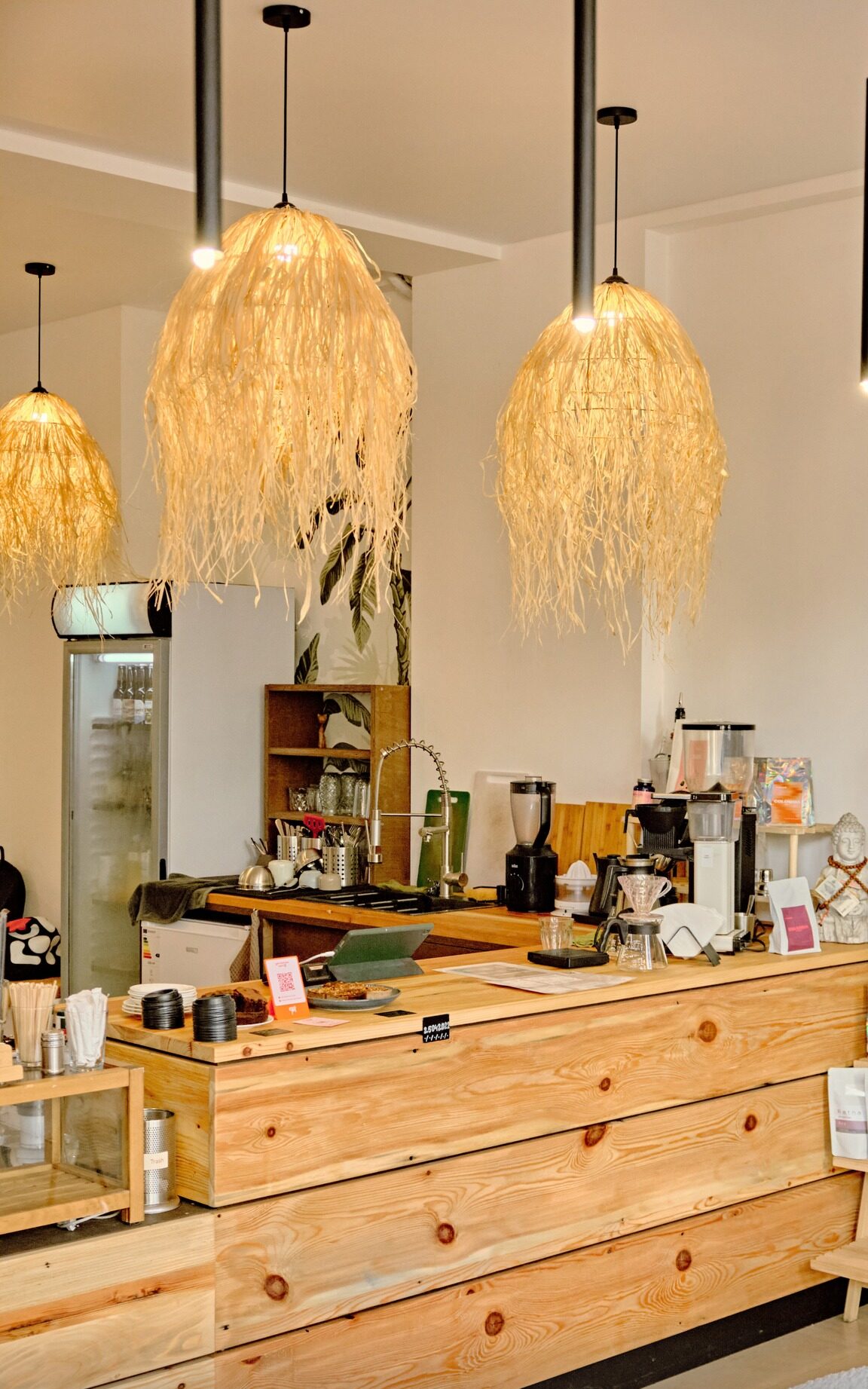 The wooden counter with coffee grinders, a V60 dripper and raffia lamps overhead
